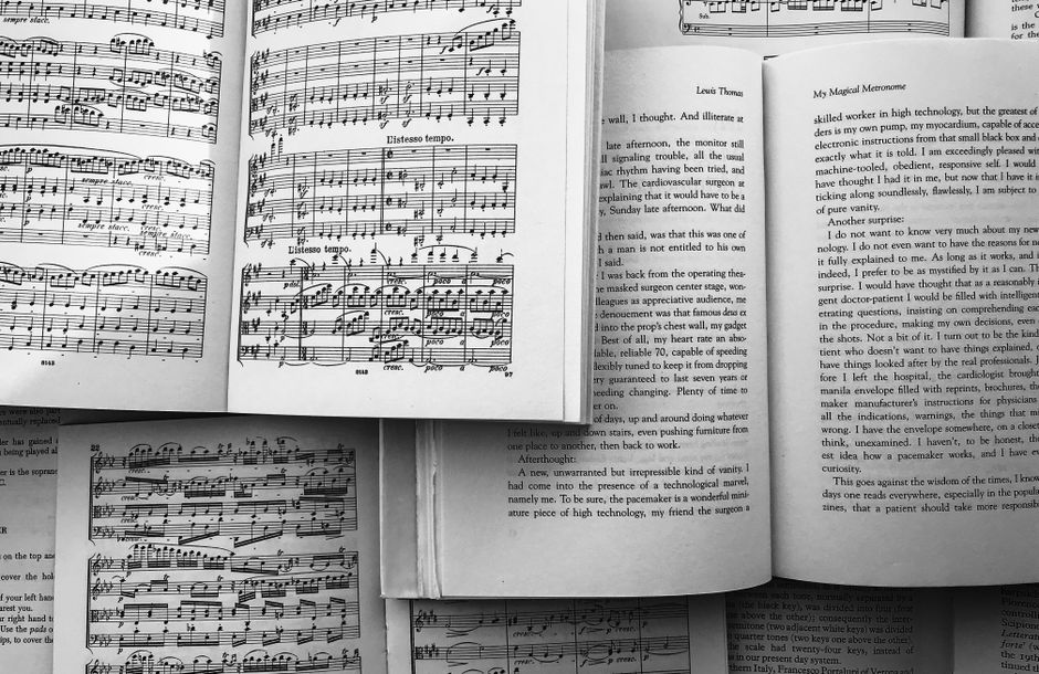 Black and white still life of open books and musical scores, showcasing harmony of literature and music.